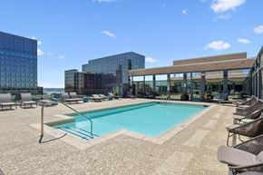 Arlington apartment for rent - A swimming pool surrounded by lounge chairs and buildings in the background.
