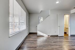Fort Collins townhouse for rent - A spacious room with wooden floors and a staircase leading to another room.