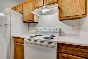 Fort Collins apartment for rent - the kitchen has a white stove and refrigerator and wooden cabinets