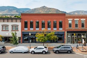 Golden apartment for rent - Cars parked in front of a red brick building with a mountain in the background.