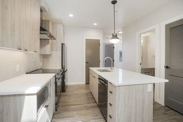 Golden apartment for rent - A modern kitchen with wooden cabinets and a white countertop.