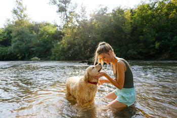 A woman is playing with her dog in the water.