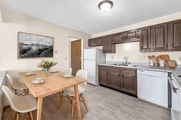 Des Moines apartment for rent - A kitchen with brown cabinets and a wooden table with chairs.