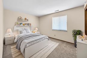 Des Moines apartment for rent - A bedroom with a large bed and a window with a blue curtain.