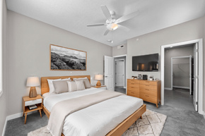 Urbandale condo for rent - A bedroom with a large bed, a ceiling fan, and a painting on the wall.