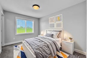 Van Meter townhouse for rent - A bedroom with a large bed and a window showing a green lawn outside.