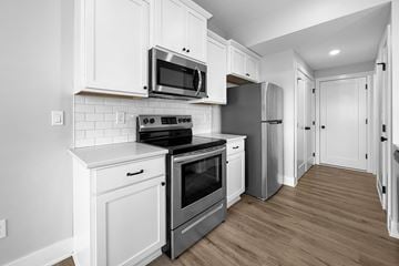 Van Meter townhouse for rent - A kitchen with white cabinets and a black stove top oven.