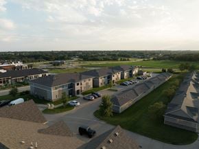 Urbandale condo for rent - A large building complex with a parking lot in front.