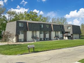Des Moines townhouse for rent - A building with a grey roof and white walls with a bench in front of it.