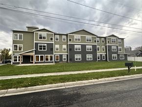 Hamilton apartment for rent - Apartment building with grey and white exterior on a cloudy day.