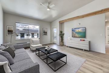 Helena apartment for rent - A living room with a grey couch, a black coffee table, and a white cabinet with a painting on it.