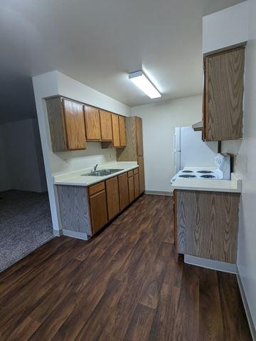 Seaside apartment for rent - an empty kitchen with wooden cabinets and a stove and refrigerator