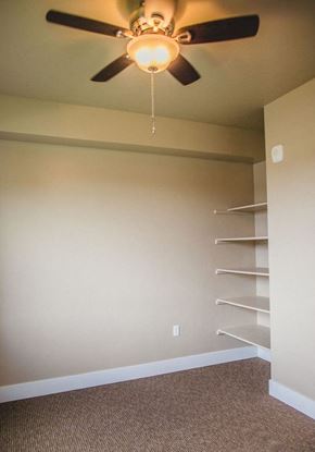 Caldwell apartment for rent - a ceiling fan hanging from a ceiling in a bedroom with shelving