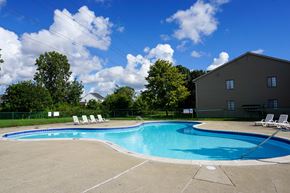Clinton Twp apartment for rent - Swimming Pool and pool chairs with apartment in background, at Garfield Commons