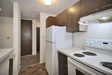 Flint apartment for rent - A white fridge and stove in a kitchen with brown cabinets.