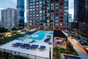 Jersey City apartment for rent - A large swimming pool surrounded by a black fence and several lounge chairs.