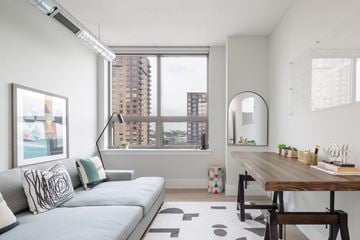 Jersey City apartment for rent - A modern living room with a grey sofa and a wooden table.