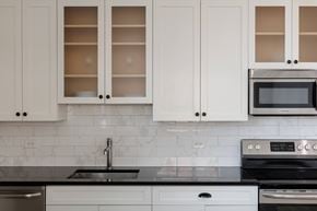 Jersey City apartment for rent - A kitchen with white cabinets and black countertops.