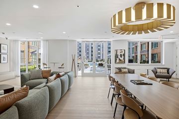 West New York apartment for rent - A long wooden table is surrounded by chairs in a room with a large window.