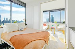 Jersey City apartment for rent - A bedroom with a large bed and a view of the city.