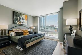 Jersey City apartment for rent - A bedroom with a large bed and a view of the city.