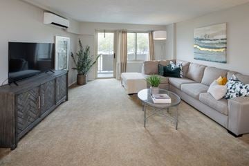 Cherry Hill apartment for rent - A living room with a grey couch, a glass coffee table, a wooden cabinet, a flat screen TV, and a painting on the wall.