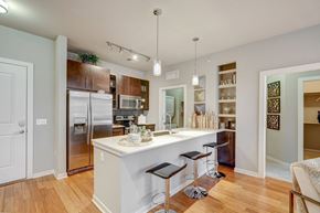 Denver apartment for rent - Kitchen with island, white quartz counters and dark cabinets at ALARA Union Station Apartment Homes, Denver, 80202