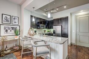 Dallas apartment for rent - a kitchen with a marble counter top and a bar with chairs