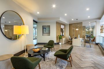 Los Angeles apartment for rent - A modern living room with a green chair and a round mirror on the wall.