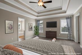 Loganville apartment for rent - Another perspective view of the serene primary suite, showcasing a modern ceiling fan, sleek entertainment, and sunlit window views.