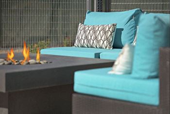 A living room with blue couches and a fire pit
