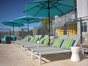 A row of lounge chairs with umbrellas on a patio