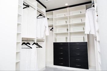 A large closet with black drawers and white closets