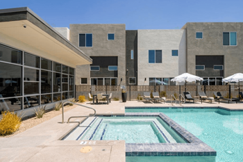 A swimming pool with chairs and a building in the background
