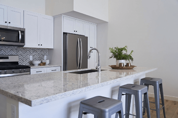 A kitchen with bar stools and a granite counter top