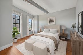 Jersey City apartment for rent - A bedroom with a large bed and a plant in a pot.