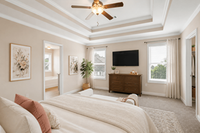 Loganville apartment for rent - Another perspective view of the serene primary suite, showcasing a modern ceiling fan, sleek entertainment, and sunlit window views.