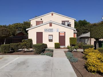 Los Angeles apartment for rent - A building with a sign on it and bushes in front.