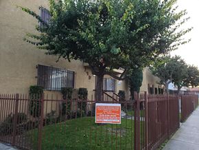 Los Angeles apartment for rent - A sign is posted on a fence in front of a building.