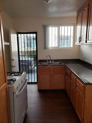 Los Angeles apartment for rent - A kitchen with wooden cabinets and a white stove top oven.