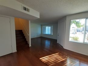 Canoga Park apartment for rent - A room with wooden floors and a staircase leading to another floor.