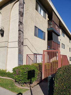 San Pedro apartment for rent - an exterior view of an apartment building with a red gate