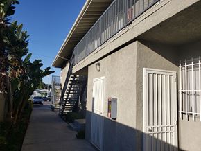 Los Angeles apartment for rent - A concrete building with a metal gate and a staircase leading to the second floor.