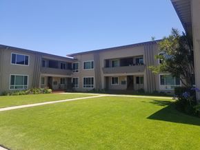 Los Angeles apartment for rent - A sunny day at the courtyard of a beige building with green grass.