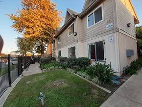 Los Angeles apartment for rent - A beige house with a black fence and a tree with yellow leaves.