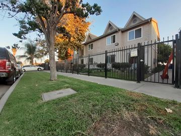 Los Angeles apartment for rent - A tree with yellow leaves stands in front of a house with a black fence.