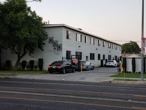 Los Angeles apartment for rent - A black car is parked in front of a white building.