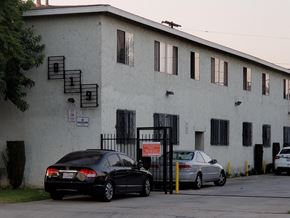 Los Angeles apartment for rent - A black car is parked in front of a white building with a gate.