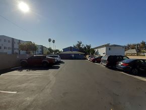 Los Angeles apartment for rent - A parking lot with cars and buildings under a clear sky.