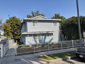 Los Angeles apartment for rent - A house with a grey facade is surrounded by a white fence.